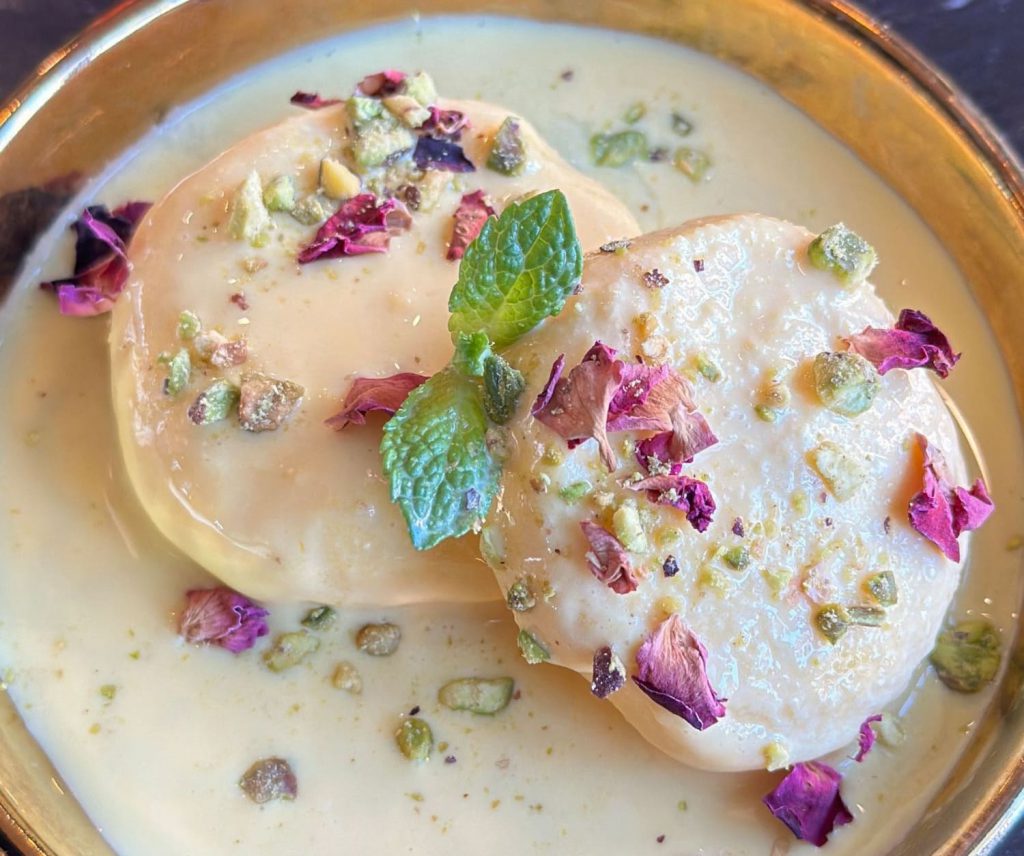Soft ras malai soaked in saffron milk and garnished with pistachios